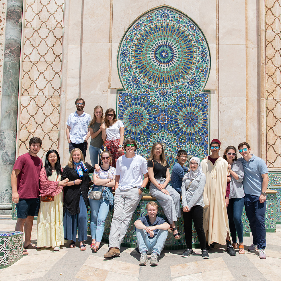 A group of students pose for a picture in front of a tiled fountain