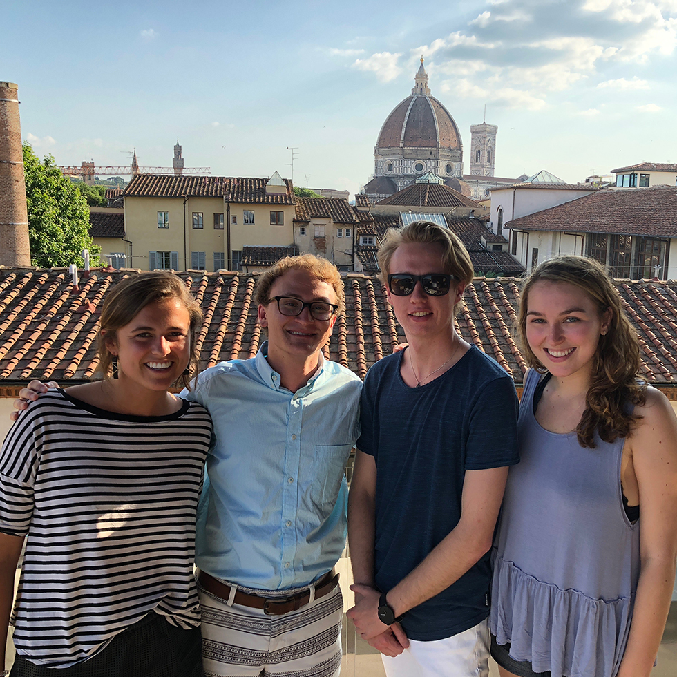 A group of students standing on a balcony with the Florence Duomo in the distance