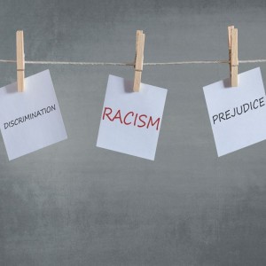 An image of notes pinned to a clothes line with the word DISCRIMINATION, RACISM, and PREJUDICE