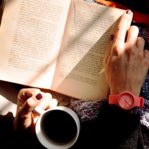 Woman holding an open book with a cup of coffee