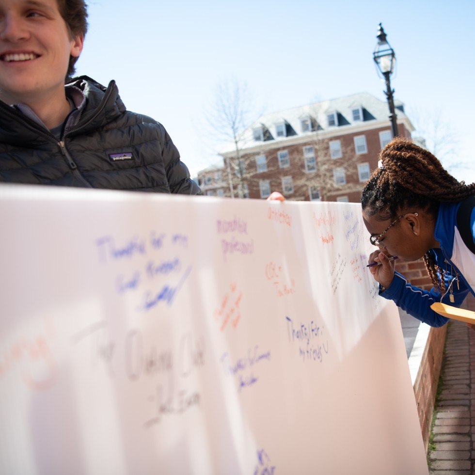 Photo of a student signing a banner during Say Thanks Week