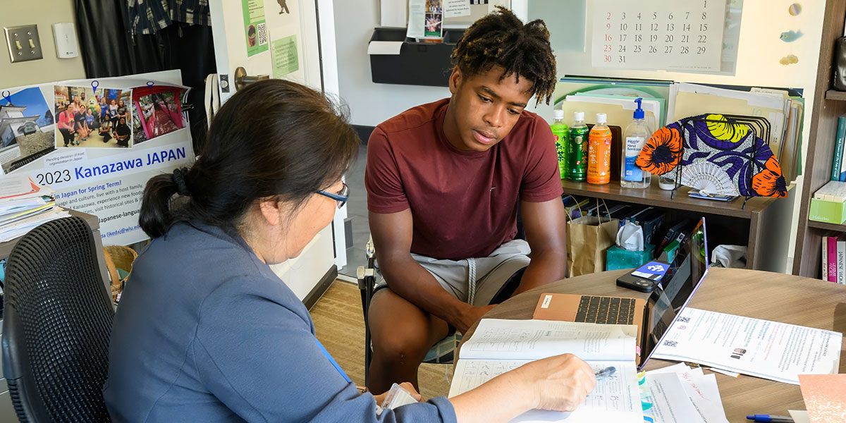 A professor helps a student register for classes.