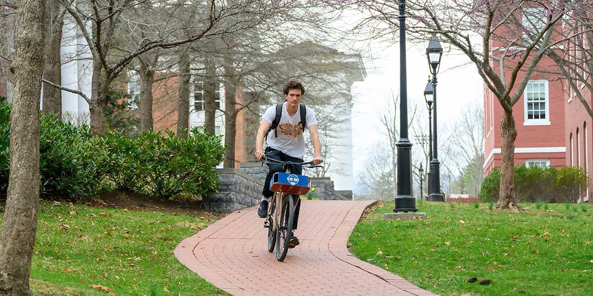 Student riding a Blue Bike on campus