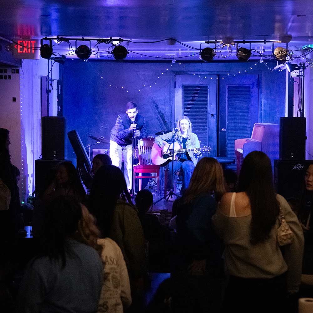 Two students perform on stage at a Friday Underground event.